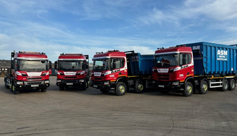 Four ASM hookloader trucks lined up in a yard